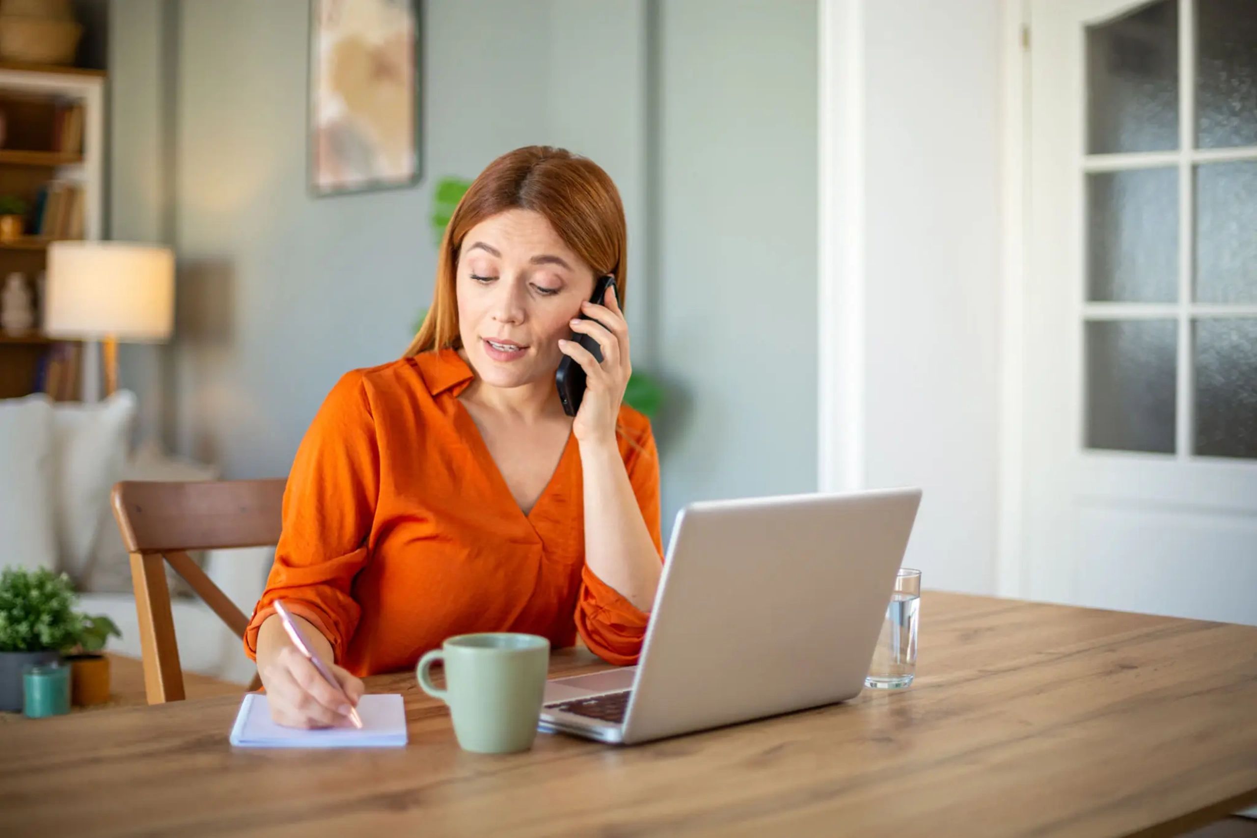 Woman taking notes during a phone call at her desk
